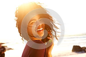 Carefree young woman with curly hair laughing outdoors
