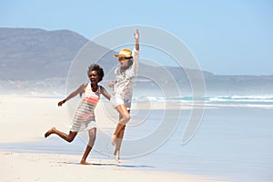 Carefree young women walking barefoot on beach