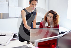 Careful critiquing. two attractive designers at work on a computer in the office.