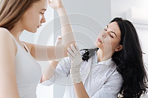 Careful dermatologist disinfecting patient arm in the clinic