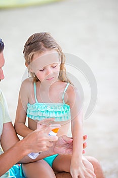 Careful father applying sun cream to kid nose. Portrait of lttle girl in suncream