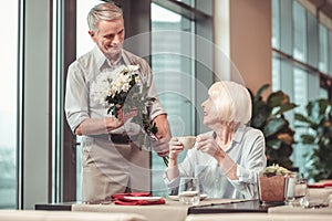 Careful man giving flowers to a retired lady