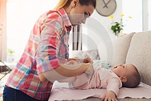 Careful Mother Swaddle Little Baby on Light Couch