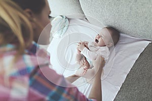 Careful Mother Swaddles Crying Baby on Couch