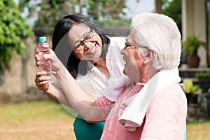 Careful senior woman giving a bottle of water to her partner out