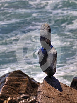 Carefully balanced stones on an ocean jetty