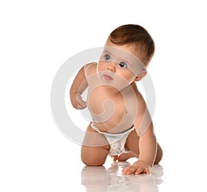 Carefully listening attentive infant baby toddler in diaper stands crawls on all fours touching his side