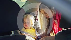 By carefully putting a child in a car seat, a woman guarantees her safety