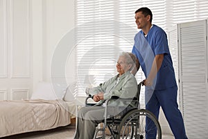 Caregiver assisting senior woman in wheelchair. Home health care service