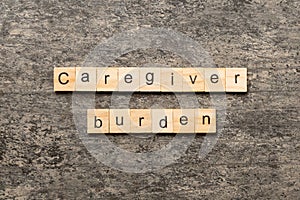 Caregiver burden word written on wood block. Caregiver burden text on cement table for your desing, concept