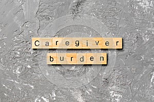 Caregiver burden word written on wood block. Caregiver burden text on cement table for your desing, concept