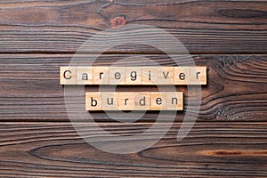 Caregiver burden word written on wood block. Caregiver burden text on cement table for your desing, concept