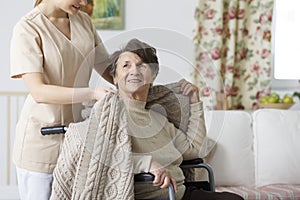 Caregiver covering senior woman with a blanket