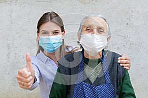 Caregiver with elderly ill woman showing thumbs up