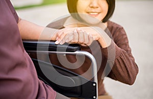 Caregiver hand holding to asian elderly woman sitting on wheelchair,Take care and support,Senior insurance concept