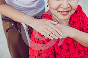 Caregiver hands holding to elderly asian woman sitting on wheelchair,Senior insurance concept photo