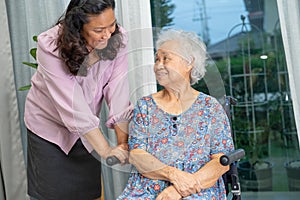 Caregiver help Asian senior woman on wheelchair with love at home