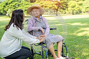 Caregiver help and care Asian senior or elderly old lady woman patient sitting on wheelchair in park, healthy strong medical