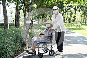 Caregiver help and care Asian senior or elderly old lady woman patient sitting on wheelchair and wear a face mask to travel in