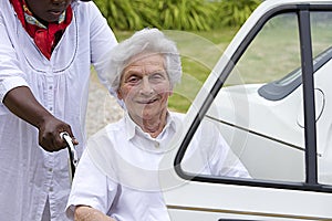 Caregiver helping a disabled lady to get into the car