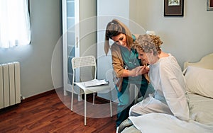 Caregiver helping elderly patient to get out of bed