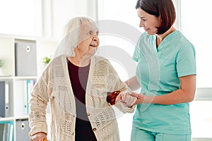 Caregiver helping elderly woman to walk