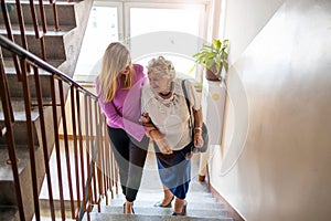 Caregiver helping senior woman climb staircase