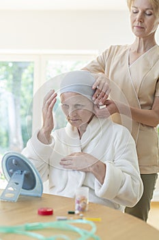 Caregiver helping senior woman with headscarf