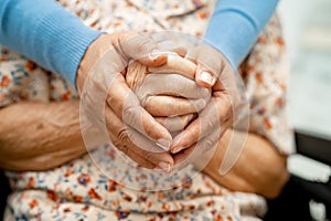 Caregiver holding hands Asian elderly woman patient with love, care, encourage and empathy at nursing hospital, healthy strong photo