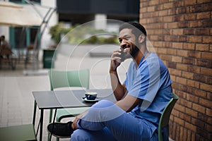 Caregiver man calling and sitting, outdoor at cafe.