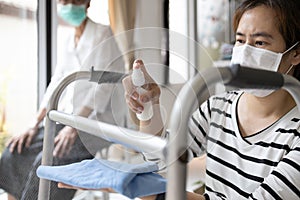 Caregiver in a mask,using spraying alcohol antiseptic,disinfecting spray,cleaning on walking aids,walker for the senior,during photo