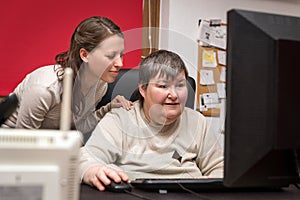 Caregiver and mentally disabled woman learning at the computer photo