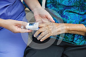 Caregiver monitoring oxygen saturation at fingertip of elderly