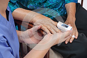 Caregiver monitoring oxygen saturation at fingertip of elderly woman