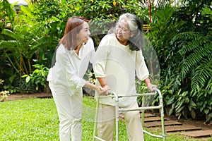 A caregiver or nurse does physical therapy for an elderly person in an outdoor garden.