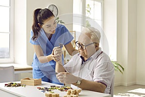 Caregiver or nurse in retirement home helping demented senior patient with games and puzzles photo