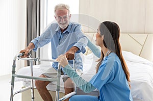 Caregiver nurse take care a Senior patient. Nurse helping senior Man hand holding walker trying to walk