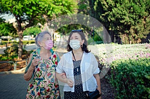 Caregiver and an old woman strolling in face masks