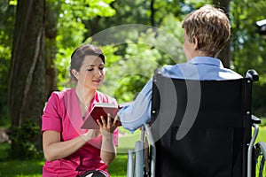 Caregiver reading a book to disabled woman