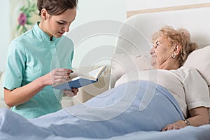 Caregiver reading ill patient book