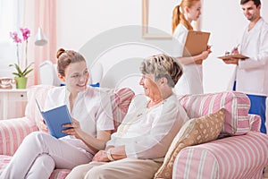 Caregiver reading to old patient