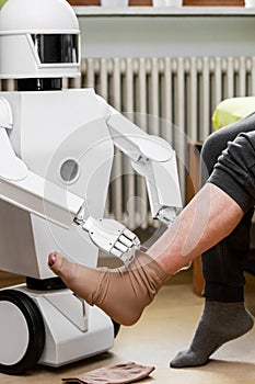 Caregiver robot or medical assisted living robot is putting on a compression stocking