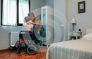 Caregiver showing the view through the window to elderly patient