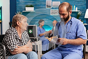 Caregiver support nurse reading book stories to senior disabled pensioner