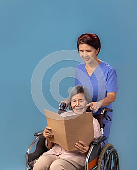 Caregiver takecare elderly woman on wheelchair at nursing home.