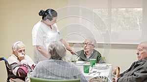 Caregiver talking to senior man in canteen at nursing home