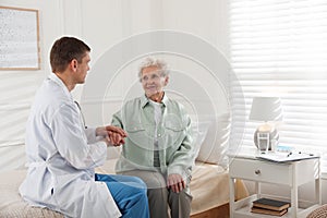 Caregiver talking to senior woman in living room. Home health care service