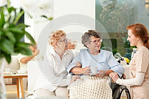 Caregiver talking to a smiling senior woman and her friend in th