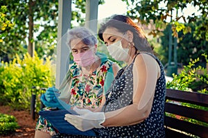 Caregiver teaching an elderly woman how to enjoy a digital tablet.