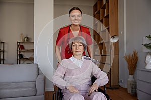Caregiver woman preparing elderly lady in wheelchair for walk